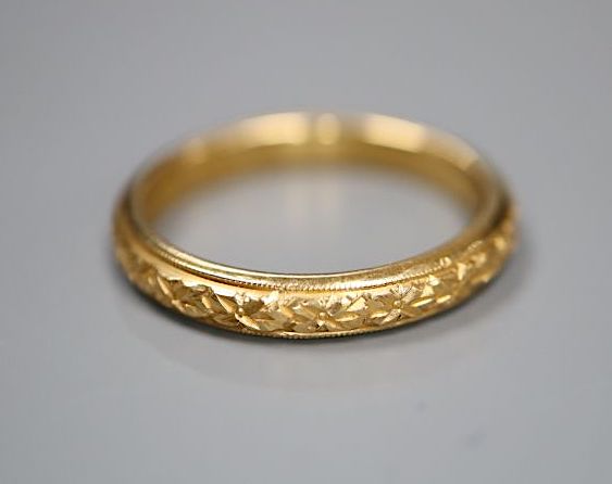A late Victorian carved 22ct gold wedding band, size N/O,